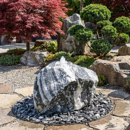 Ein massiver Quellstein Findling aus Wachauer Marmor positioniert als zentrales Gestaltungselement einem japanischen Steingarten